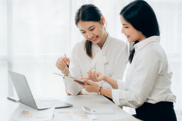 Obraz premium Two business Asian young women working together with laptop computer in the modern office.