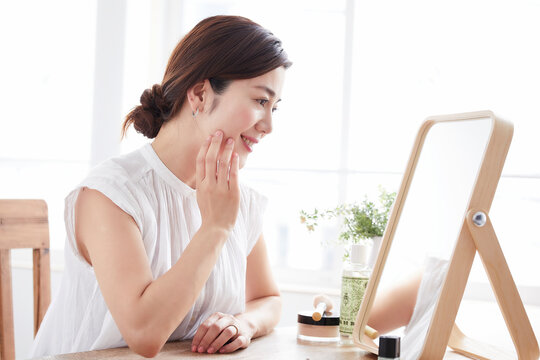 鏡を見ながら肌の手入れをする女性