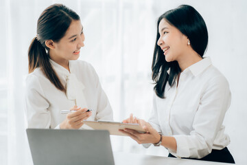 Two business Asian young women working together with laptop computer in the modern office.