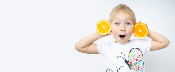 Surprised blonde child girl holding two cut halves of an orange on a white background. Banner