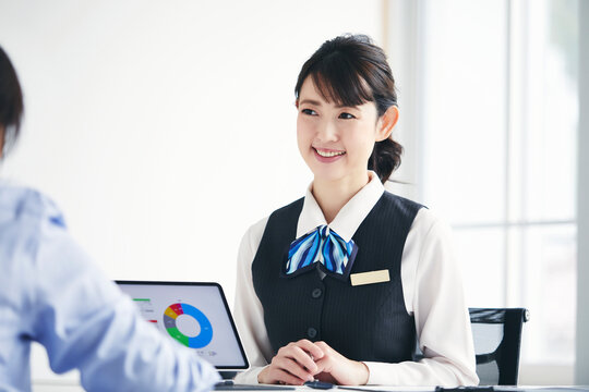 制服を着てタブレット端末を使い説明をする女性