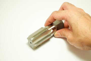 Mechanic's hand tapping threads on a white background,concept of choosing a thread size,screw hand...