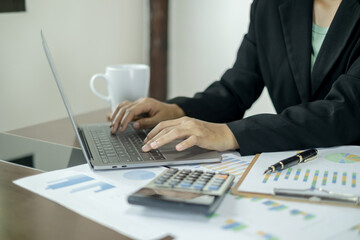 Asian female accountants sit at their desks and calculate financial graphs showing results about their investments, planning a successful business growth process