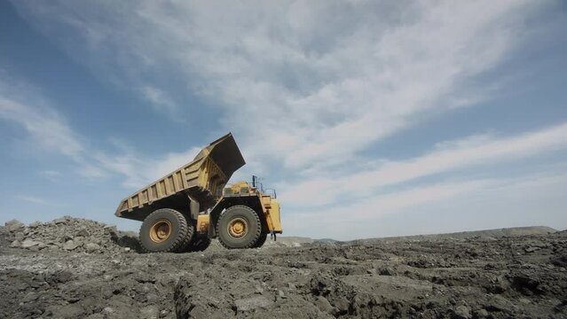 Multi-ton dump truck folds its body and leaves after unloading waste rock. Element of coal mining process