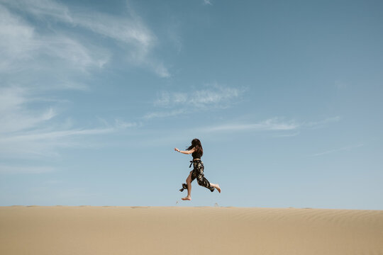 Woman jumping on sand land and blue sky at sunset