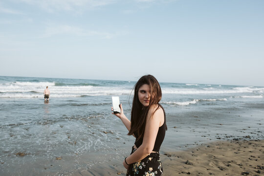 young woman taking pictures at beach