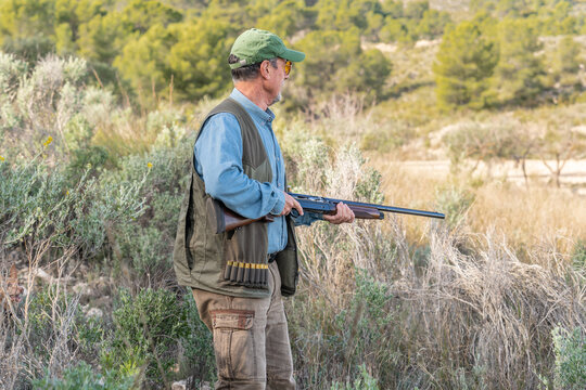 Huntsman with rifle in green field