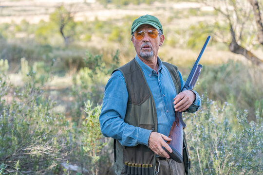 Huntsman with rifle in green field