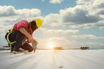 Construction workers work installing new roofs on houses and buildings. Use an electric drill to...
