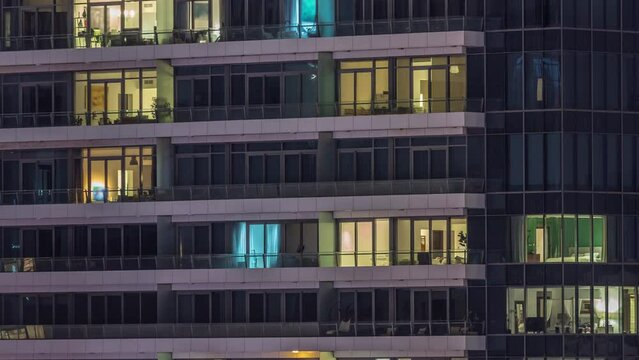 Windows lights in modern office and residential buildings timelapse at night. Multi-level skyscrapers with illuminated apartments inside