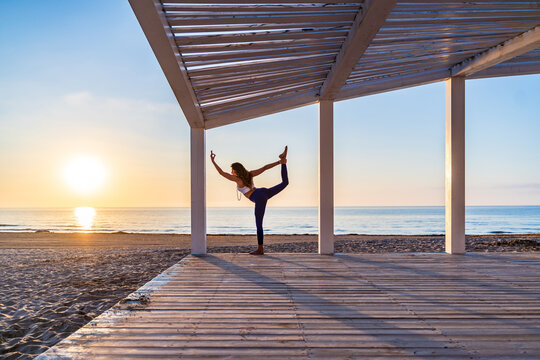Woman doing yoga in standing split pose at seaside