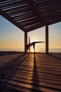 Woman doing yoga in standing split pose at seaside