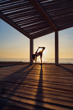 Woman doing yoga in standing split pose at seaside