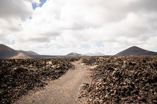 Amazing volcano landscape with rough rocky terrain under cloudy sky in Spain