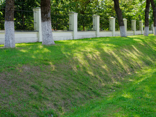 brick fence with a lawn around a green park