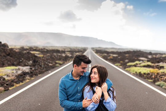 Young stylish couple embraced and walking on road in highland