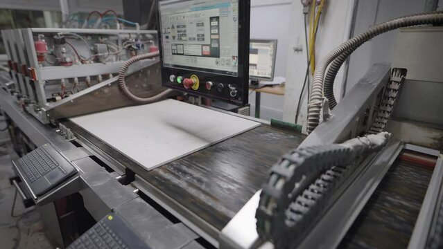 An industrial printer in a porcelain tile factory. The printer applies a pattern and texture to the board blank.