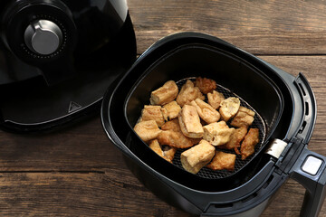 homemade fry tofu and fry taro are cooked by using a black air fryer or oil free fryer appliance for being lunch in afternoon party with background of old vintage wooden table in the dinning room.