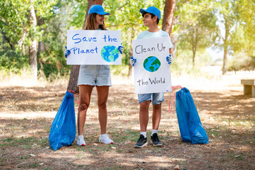 Woman and child volunteers picking up litter and holding a Clean Up the World and save the planet...