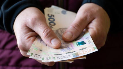 White male shows Ukrainian hryvnia bills in his hand closeup front view