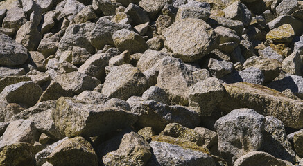 Large boulders lie on a heap of construction and garden rocks 