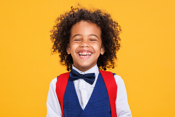 Happy curly schoolboy on color yellow background