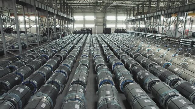 Industrial warehouse of a metallurgical enterprise. Rolled metal products are stored in rows in a warehouse.
