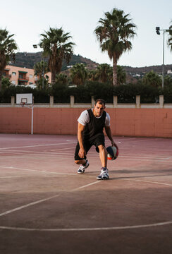 Pensive adult man playing basketball on court