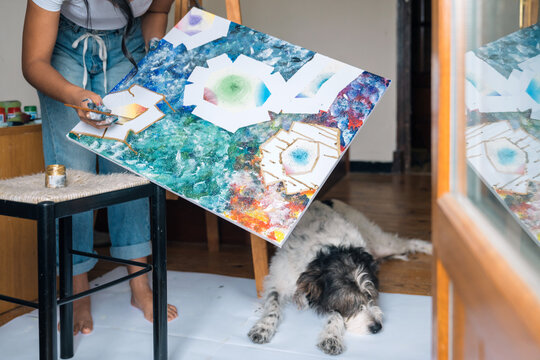 Crop faceless artist drawing on canvas bear sleeping dog