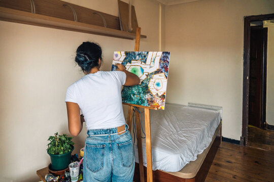 Unrecognizable female artist drawing on canvas with paintbrush