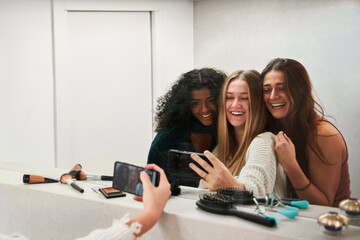 Joyful diverse women taking selfie in dressing room