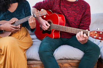 Diverse friends playing guitar and ukulele on terrace