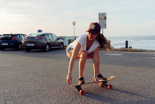 Beautiful skater practicing riding skate board on street