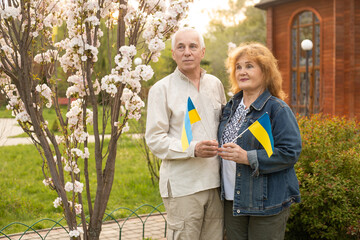 Naklejka na ściany i meble Senior couple with Ukrainian flag. Elderly man and woman in national clothes with the flag of Ukraine. Message of freedom for the Ukrainian people.
