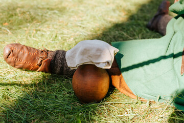 Medieval concept. Ceramic ancient jug standing at the feet of a man on green grass outdoors, close-up