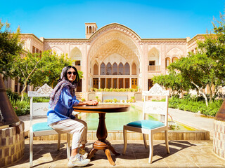 Kashan, Iran - 30th may, 2022: Caucasian female Tourist sit pose photo in Tabatabaei house mansion...
