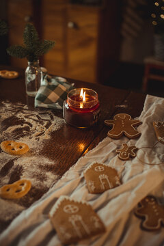 Still life in dark colors with a burning candle on the table with gingerbread cookies and gingerbread houses
