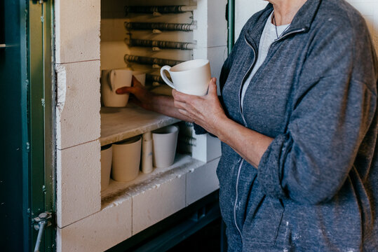 Potter putting clay cup into kiln