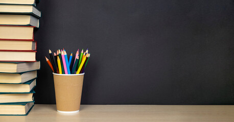 School accessories - books and pencils on the background of a black school board. Back to school...