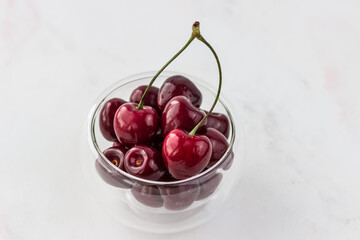 Cherries in a transparent bowl on a white background. Vitamins and a healthy lifestyle