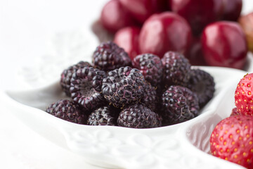 Close-up of raspberries on a fruit plate on a white background. Ripe berries. Vitamins and a healthy lifestyle