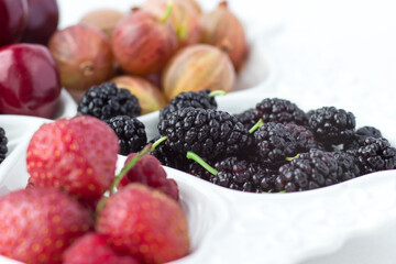 Mulberry on a fruit plate on a white background. Ripe berries. Vitamins and a healthy lifestyle