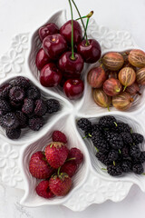 Berry plate on a white background. Strawberries, gooseberries, cherries, raspberries and mulberries