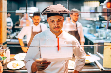 Man reading orders on paper working in kitchen