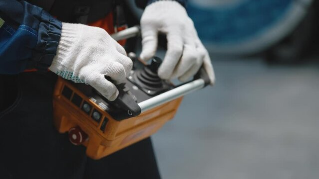 Close-up. Remote control crane beam in an industrial warehouse. The worker is loading and unloading.