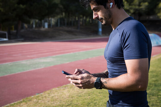 Ethnic sportsman using smartphone at stadium