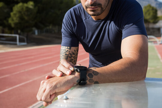 Sportsman preparing his smart watch before running on the running track