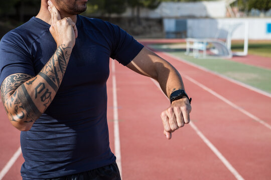 Crop sportsman counting pulse during training at stadium