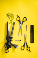 Scissors and other hairdresser's accessories on yellow background, flat lay. Space for text