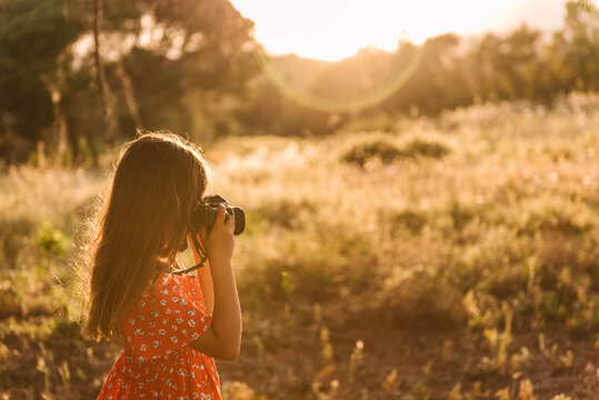 Little girl taking photo of landscape in sunny day